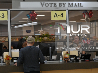 An election worker waves a US flag to assist ongoing mail-in voters during California's special election on Proposition 50, a measure that t... by Carlos Moreno/NurPhoto