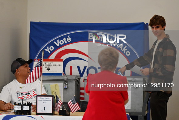 Election worker volunteer Ziba Rechou takes a picture of first-time voter Matthew Mitchell, 18, as he casts his ballot during California's s... by Carlos Moreno/NurPhoto