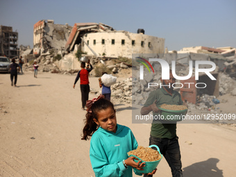 A young Palestinian girl waits with her pot to receive a portion of food at a shelter where families live in Gaza City, on November 5, 2025.... by Majdi Fathi/NurPhoto
