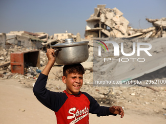 A young Palestinian boy carries a pot of rice he receives at a shelter where families live in Gaza City, on November 5, 2025.  by Majdi Fathi/NurPhoto