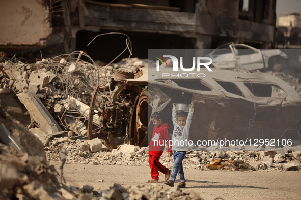 A young Palestinian boy carries a pot of rice he receives at a shelter where families live in Gaza City, on November 5, 2025.  by Majdi Fathi/NurPhoto