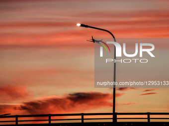 A plane flies over an urban neighbourhood as the sun sets in Krakow, Poland on November 4, 2025.  by Dominika Zarzycka/NurPhoto