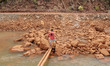 A man walks along a brown river near a nickel mining company in Kawasi village, Obi Island...
