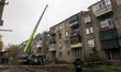 A Ukrainian police officer stands by warning tape around a residential building damaged by...