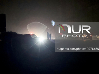 People cross a street in the light of headlights in Kharkiv, Ukraine, on November 8, 2025. Dozens of streets and neighborhoods are cut off f... by Viacheslav Madiievskyi/Ukrinform/NurPhoto