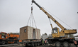 Special machinery and workers operate during the installation of houses at the site of a m...