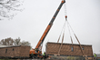 Special machinery and workers operate during the installation of houses at the site of a m...