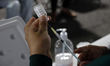 A nurse prepares a vaccine to administer to people against viral diseases of influenza, CO...