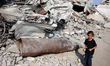 A Palestinian girl walks past an unexploded missile in the Al-Rimal neighborhood of Gaza C...