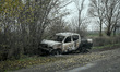 A burned-out car stands on the roadside in the frontline village of Pokrovske in the Synel...