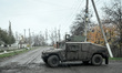 Soldiers ride in a Humvee armored vehicle along a street in the frontline village of Pokro...