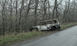 A burned-out car stands on the roadside in the frontline village of Pokrovske in the Synel...