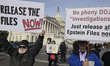 Demonstrators hold signs during the Epstein Files Transparency Act news conference in Wash...