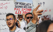 Young doctors raise a sign reading in French, ''We wanted to save lives, not bury our own,...