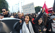 A young protester raises her fist as another holds up a sign reading in Arabic, ''the snit...