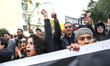 Protesters shout slogans while raising their fists and making the victory sign during a ma...