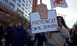 A woman holds a cardboard sign reading 'Patriarchy, we'll destroy it'. Women from the coll...