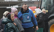 A volunteer of the Proliska humanitarian mission stays by locals affected by a Russian dro...