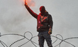 A protester holds a flare in Giessen, Germany, on November 28, 2025, during a day of natio...
