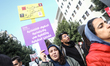 A feminist activist raises a placard reading in Arabic, ''Economic, social, and cultural r...
