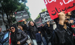 A feminist activist shouts slogans while raising a placard reading in Arabic, ''No real fe...