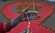 Activists light candles on a giant AIDS symbol as part of an awareness demonstration on Wo...
