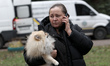 A woman holds a dog as she speaks on the phone close to the site of a Russian missile stri...