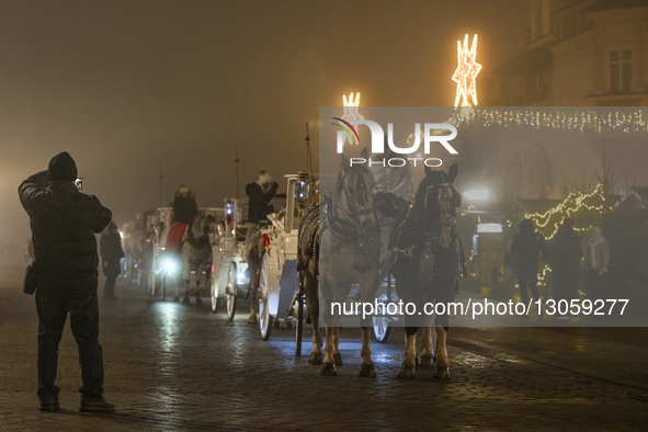 KRAKOW, POLAND – DECEMBER 4:
Horse carriages are seen stationed beside the Christmas Market in Krakow’s Main Market Square amid dense aftern... by Artur Widak/NurPhoto