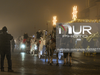 KRAKOW, POLAND – DECEMBER 4:
Horse carriages are seen stationed beside the Christmas Market in Krakow’s Main Market Square amid dense aftern... by Artur Widak/NurPhoto