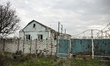 A house destroyed by Russian shelling on Partyzanska Street is behind a broken fence in Pa...