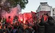 Demonstrators light flares while raising large banners featuring portraits of imprisoned p...
