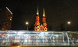 Passengers are seen at a tram stop with the Cathedral of Saint Michael in the background i...