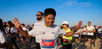 Editorial photo: A participant smiles at the camera as he approaches the finish line at the Pyramids Half Marathon in Giza, Egypt, on December 13, 2025.  by Ahmed Mosaad/NurPhoto
