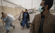 An unidentified security man monitors a convoy of unregistered Afghan refugees carrying th...