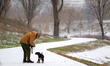 A man walks a dog along the Rusanivka Canal as it snows for the first time in winter in Ky...