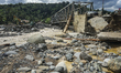 People cross a bridge damaged by a flash flood in Batu Busuk, Pauh, Padang, West Sumatra,...