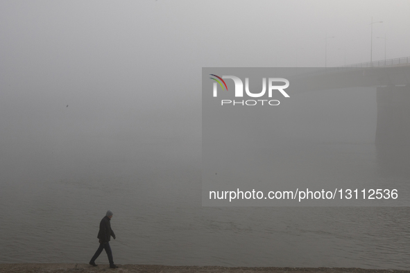 A man walks along the Danube River promenade during fog in Novi Sad, Serbia, on December 9, 2023.  by Maxim Konankov/NurPhoto