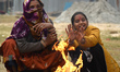 Pilgrims warm themselves by the fire before heading to Sagar Island for the one-day Makar...