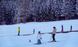 Young students practice basic techniques during a supervised group ski lesson at the base...