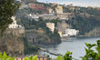 An orange tree is in the foreground at the Lucio Dalla Viewpoint, with the bay, cliffs, an...