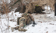 A soldier acts as a simulated casualty from a drone-dropped explosive and lies in the snow...