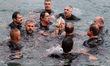 People take part in the traditional competition to catch the wooden cross during the Greek...