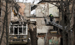 Firefighters extinguish smoldering hotspots amid debris of a multi-storey residential buil...