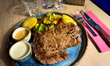 A ribeye steak served with grilled vegetables and sauces is presented in the hotel restaur...