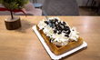 A waffle topped with whipped cream and Oreo cookie pieces is served in a pastry shop in th...