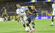 Miguel Merentiiel of Boca Juniors contests the ball with Samuel Martin of Millonarios of C...