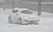 A vehicle covered in snow drives as a major winter snowstorm hits in Toronto, Ontario, Can...