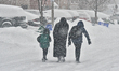 A woman and her children walk on the road as a major winter snowstorm hits in Toronto, Ont...