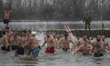 Participants swim for the cross during the traditional Epiphany celebration on the bank of...