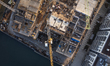 A vertical aerial drone view looks straight down onto a construction site of new riverside...